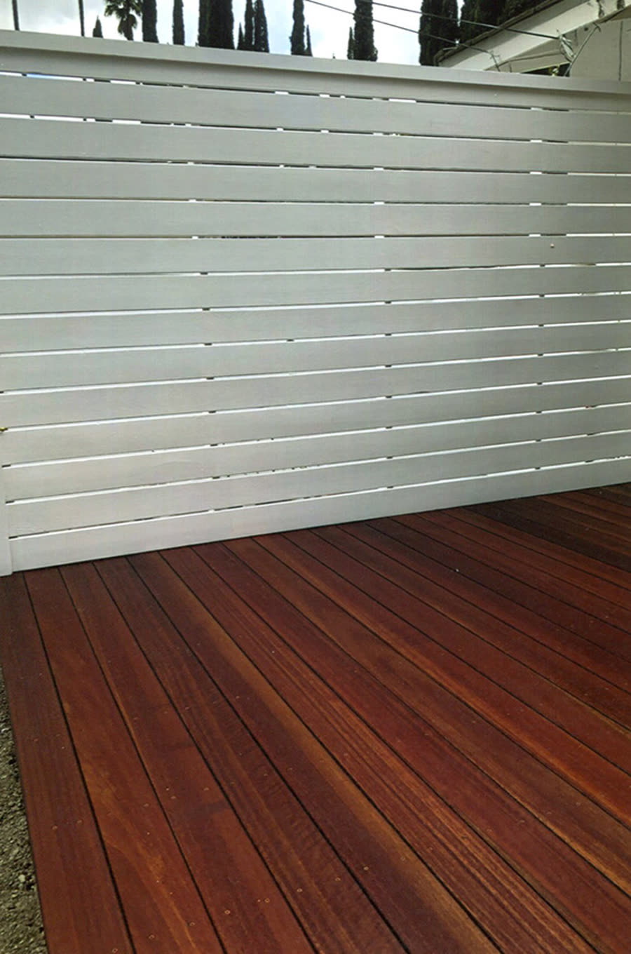 A stained wood deck with a white privacy fence.