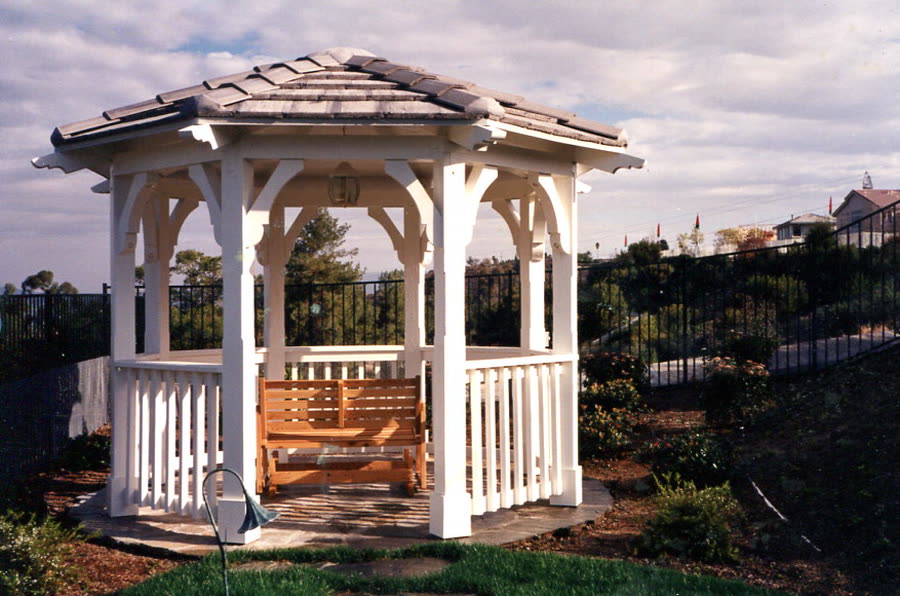 A custom gazebo with a shingle roof and a built-in bench.